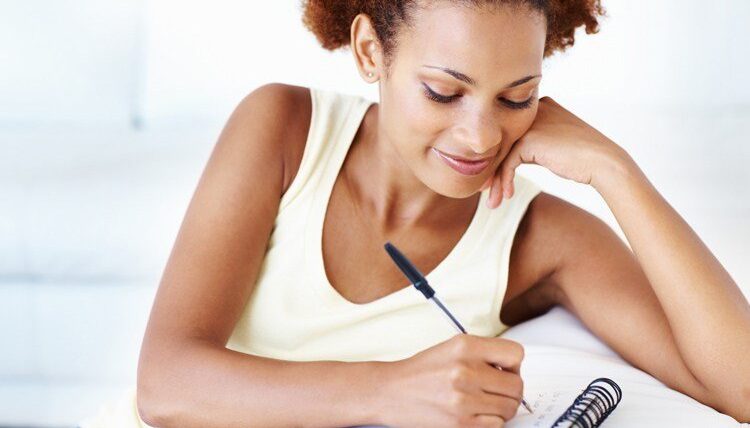 Closeup of smiling African American woman noting down writing tips