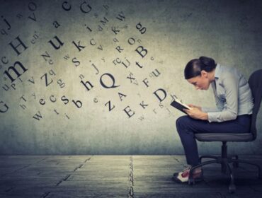 woman writing on notebook with letters coming out of it