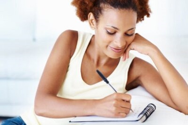Closeup of smiling African American woman writing to finish her novel