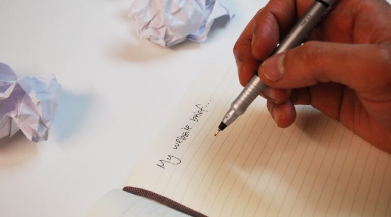 person writing a brief with a pen on a sheet of paper