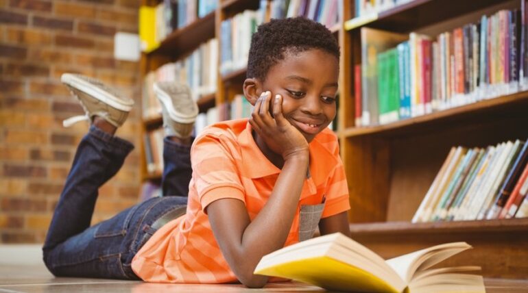 boy reading literature for children in library full of childrens books