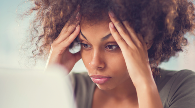 woman holding hands on head trying to write