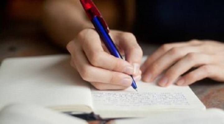 Person writing in a notebook with a pen